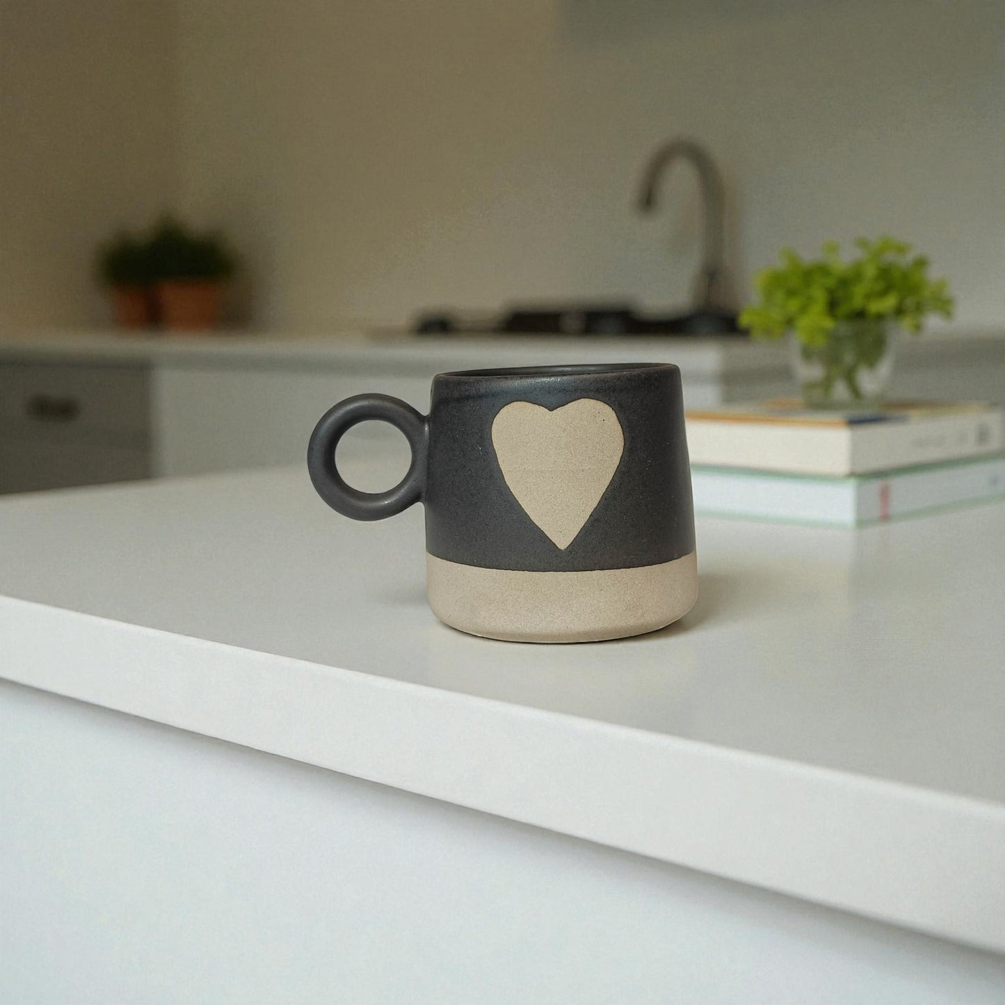 Black mug with a heart design on a white surface in a kitchen setting