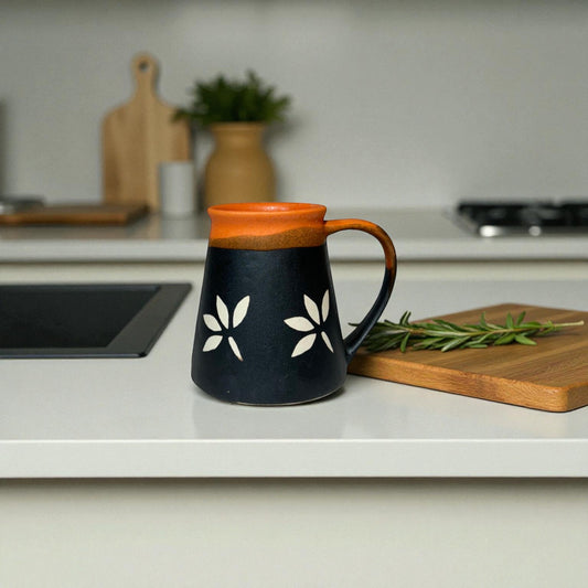 Black mug with orange rim and handle on a kitchen counter