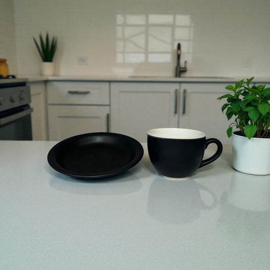 Black plate and mug on a kitchen counter with plants and cabinets in the background