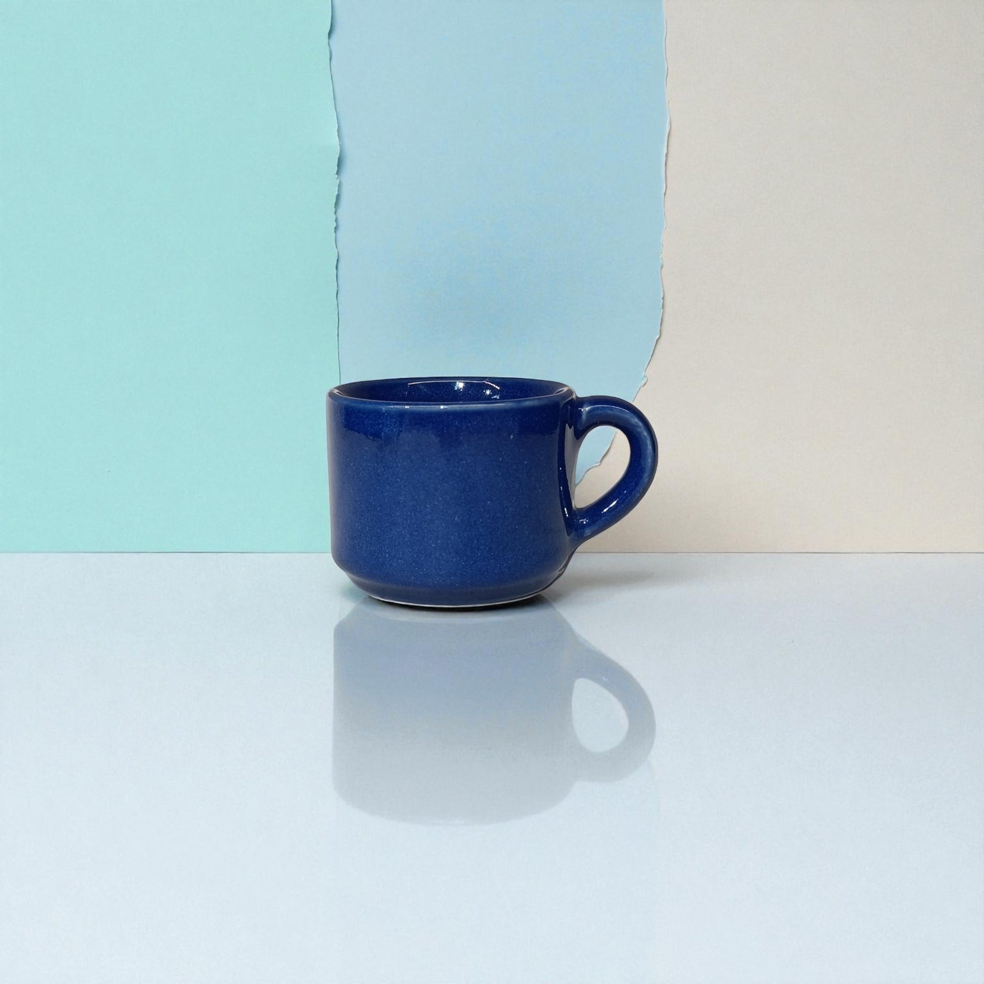 Blue mug on a reflective surface with a colorful background