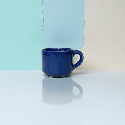 Blue mug on a reflective surface with a colorful background