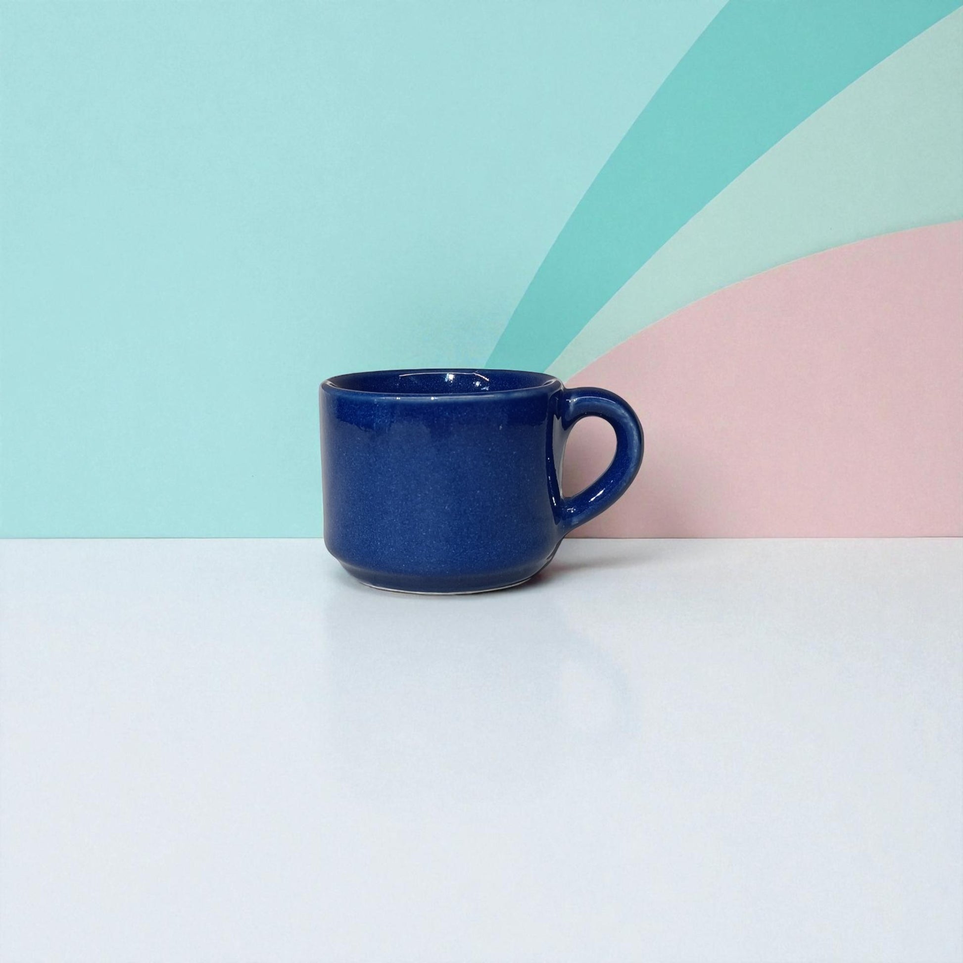 Blue mug on a white surface with a colorful geometric background
