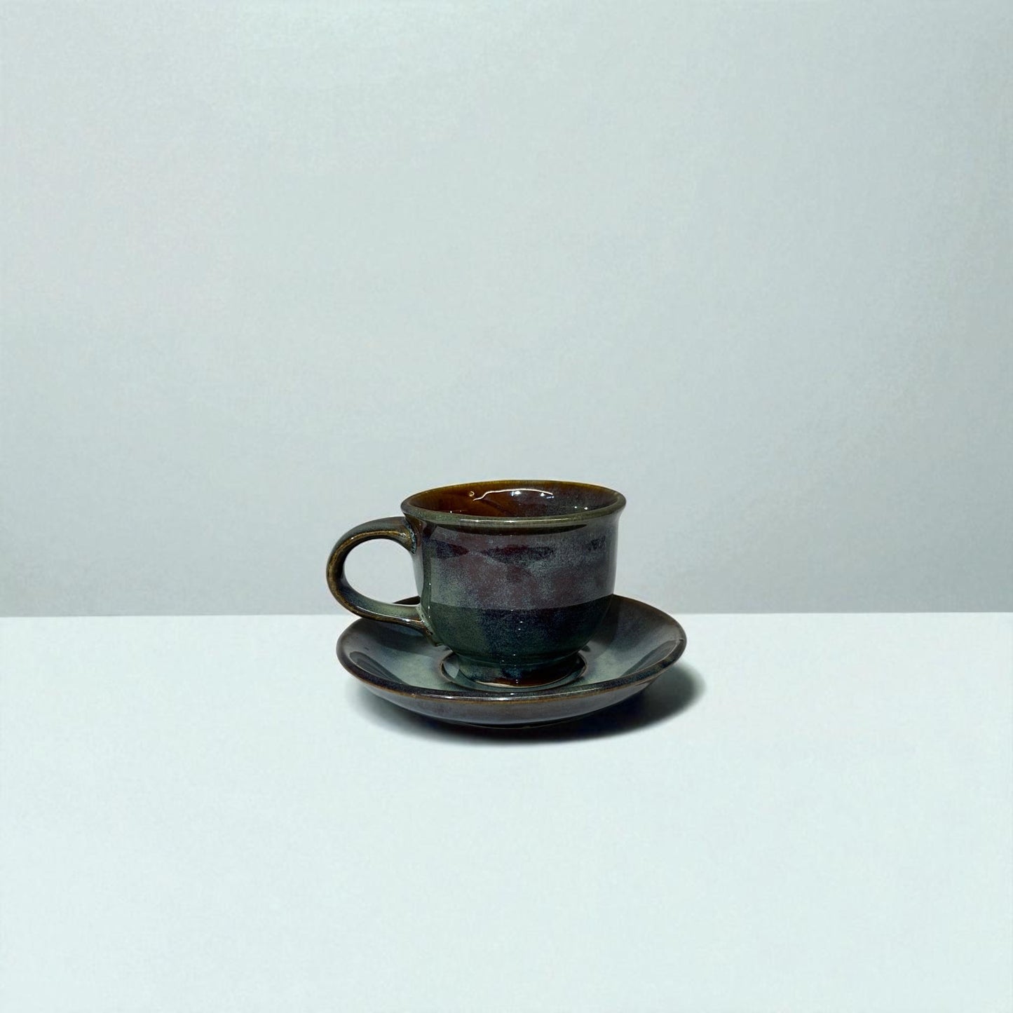 Ceramic cup and saucer on a white surface with a light gray background