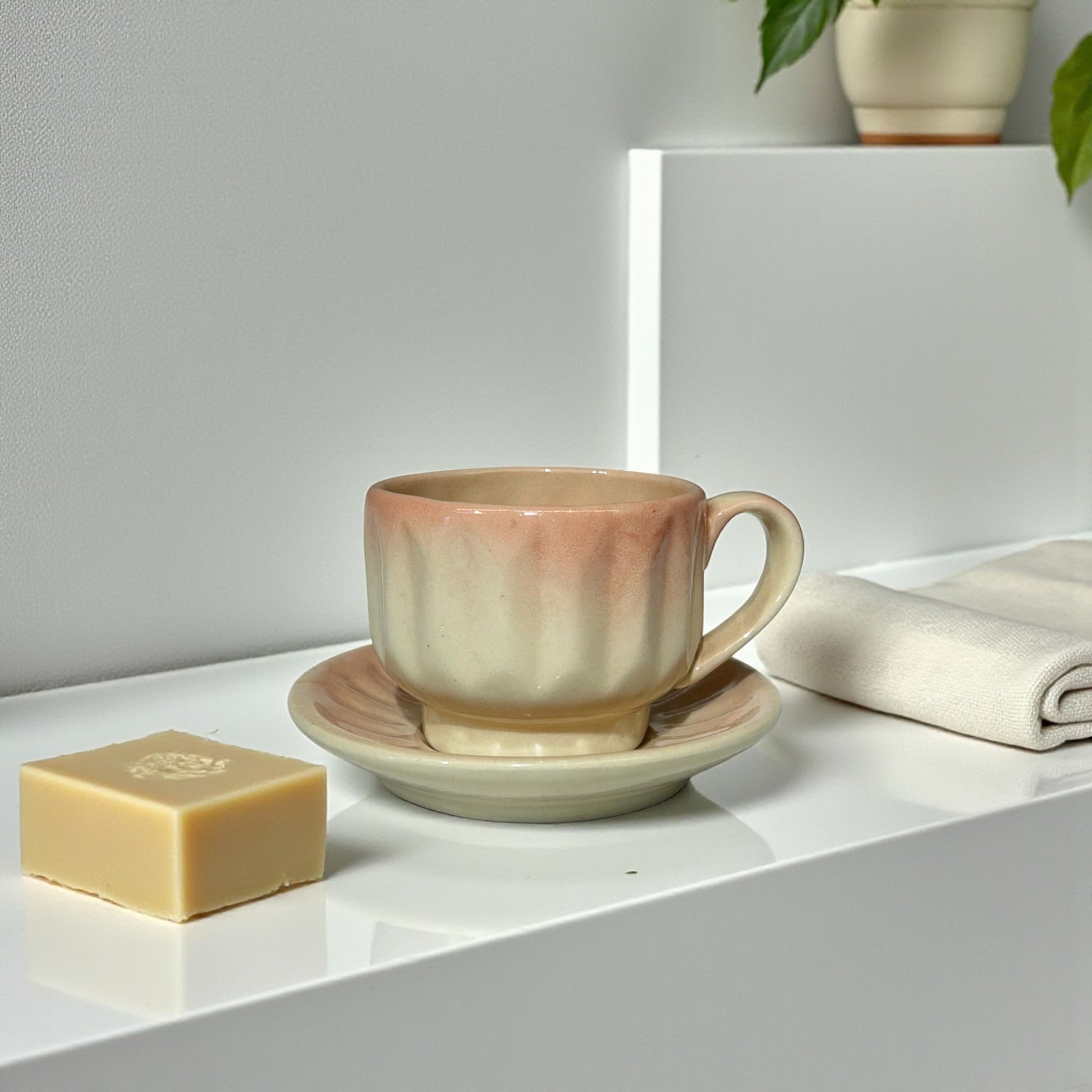 Ceramic cup and saucer with a bar of soap on a white surface