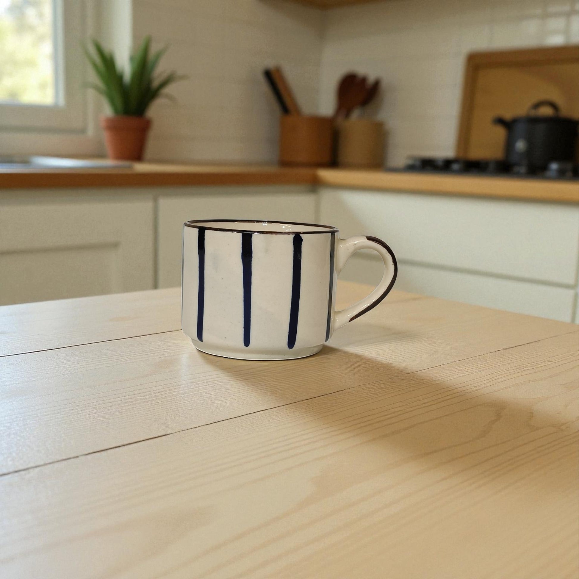 Ceramic mug with black stripes on a wooden table in a kitchen.