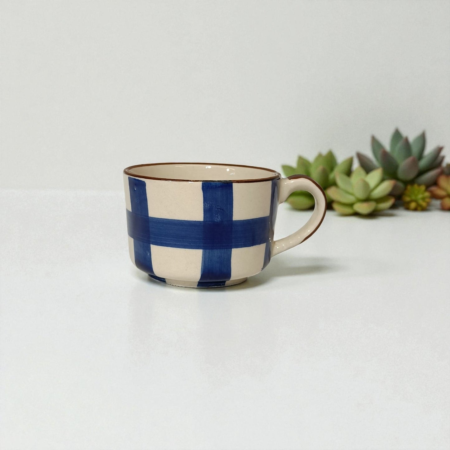 Ceramic mug with blue and white checkered pattern on a light background