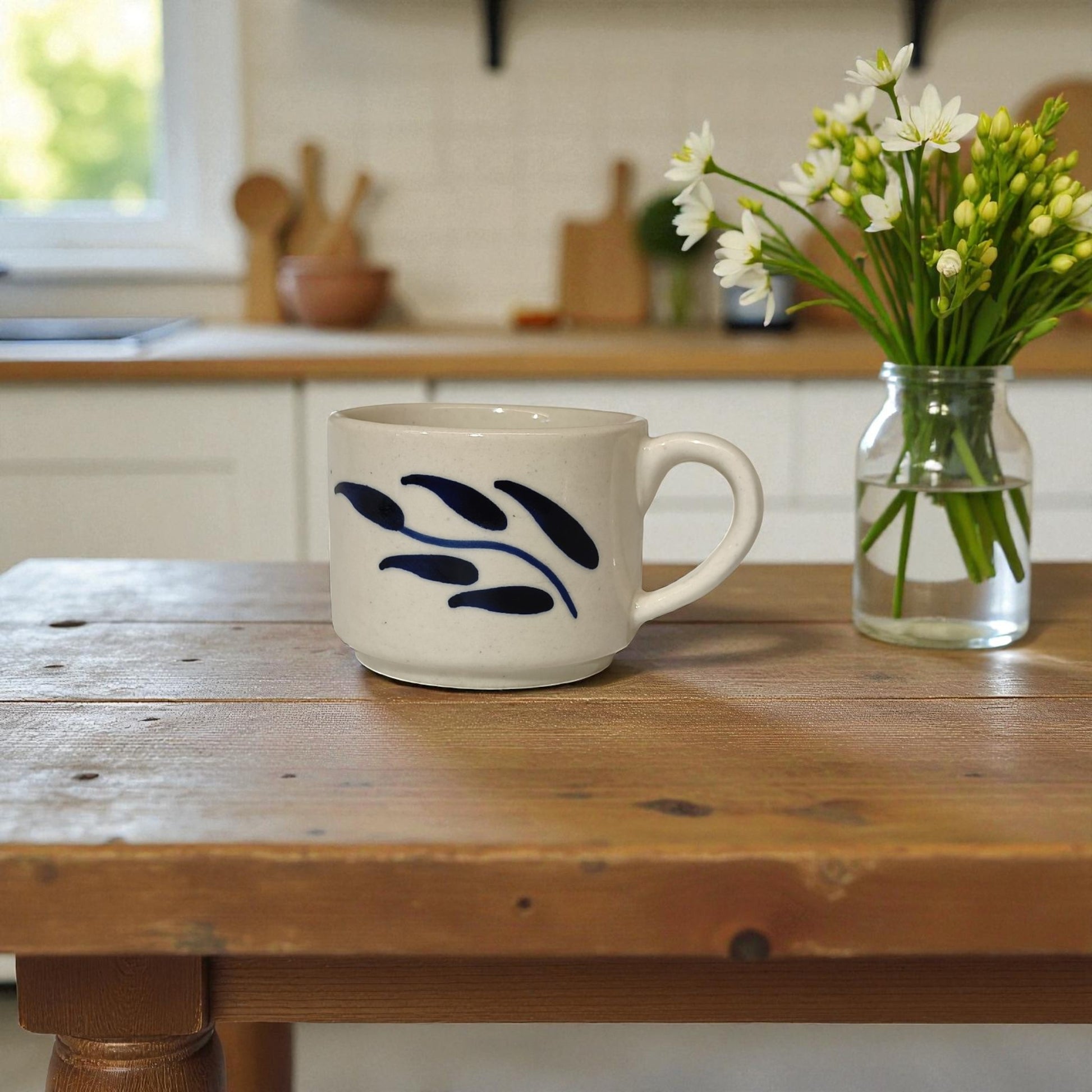 Ceramic mug with blue leaf design on a wooden table in a kitchen setting