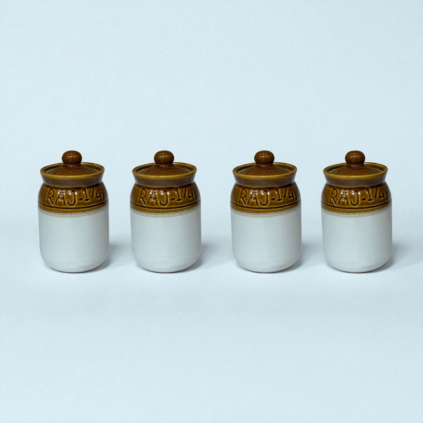 Four ceramic jars with brown lids on a light blue background
