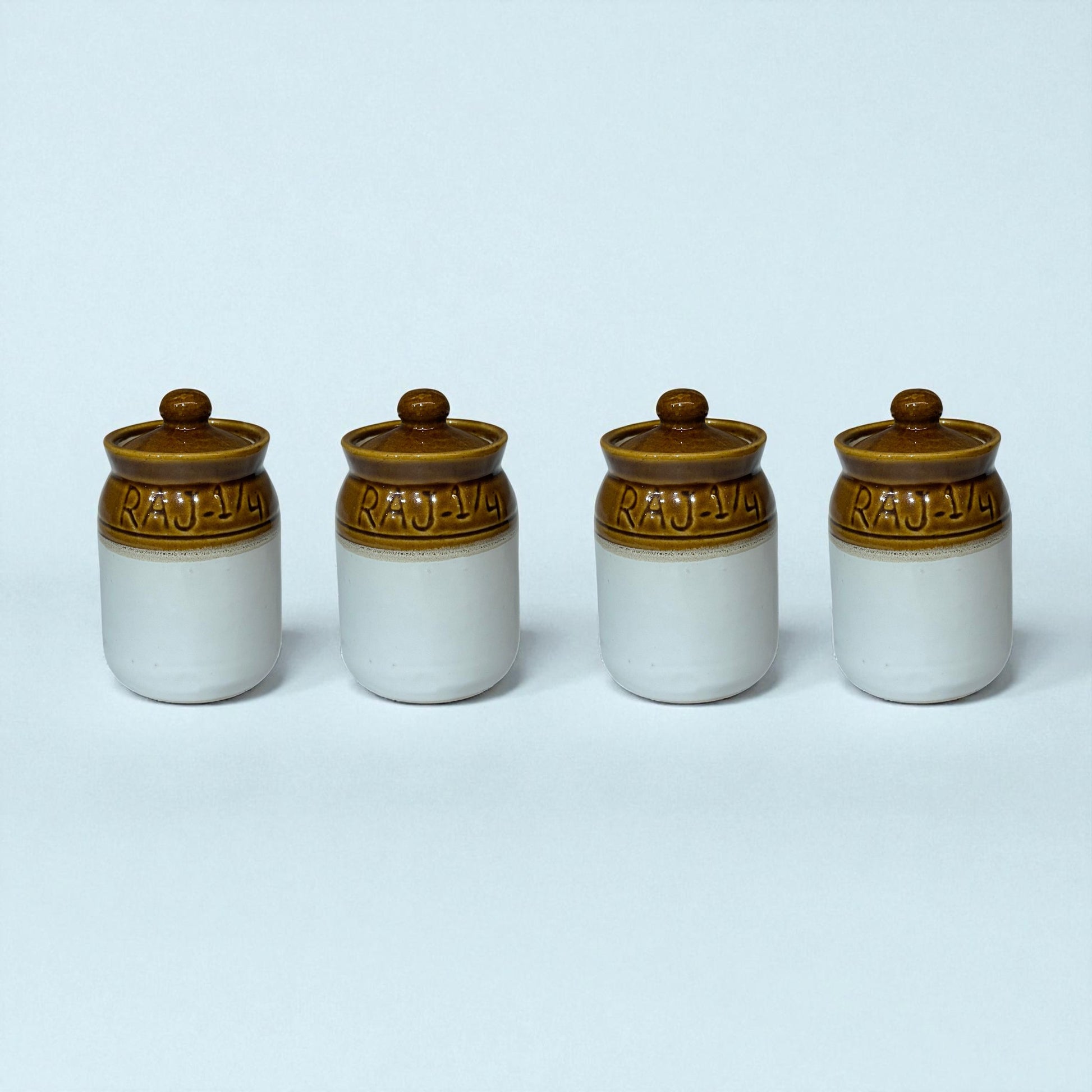 Four ceramic jars with brown lids on a light blue background