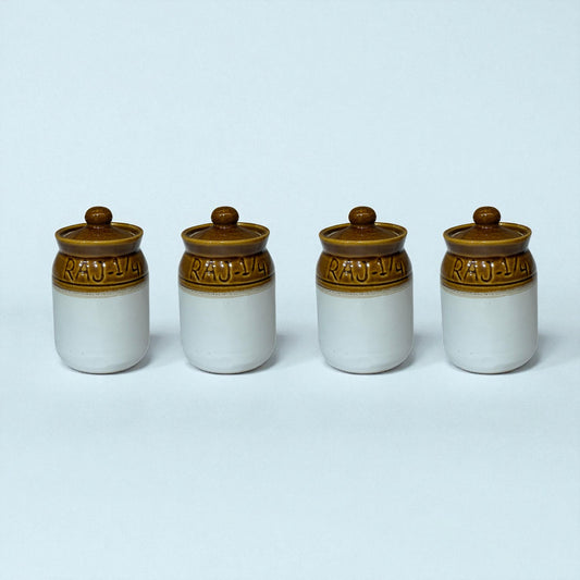 Four ceramic jars with brown lids on a light blue background