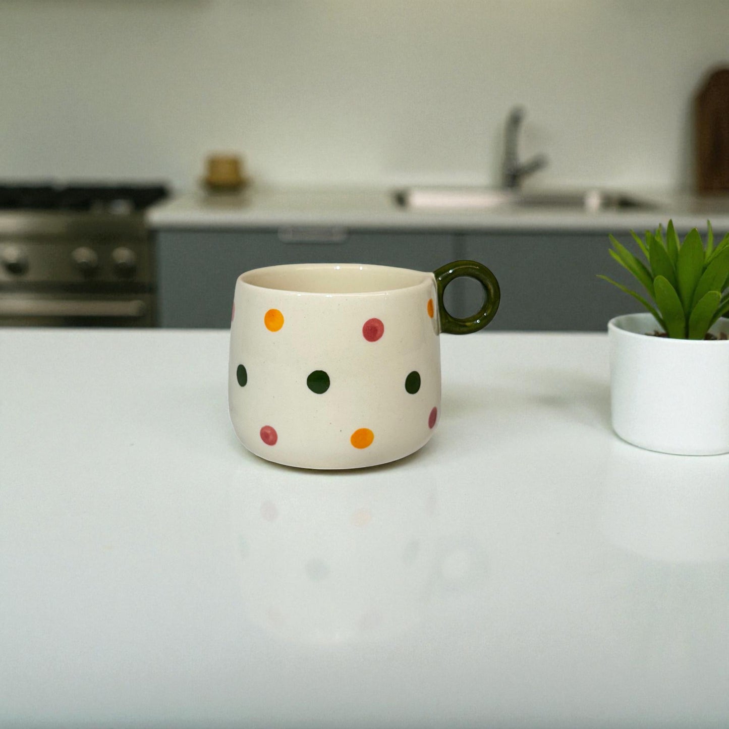 Polka dot mug on a kitchen counter with a plant in the background