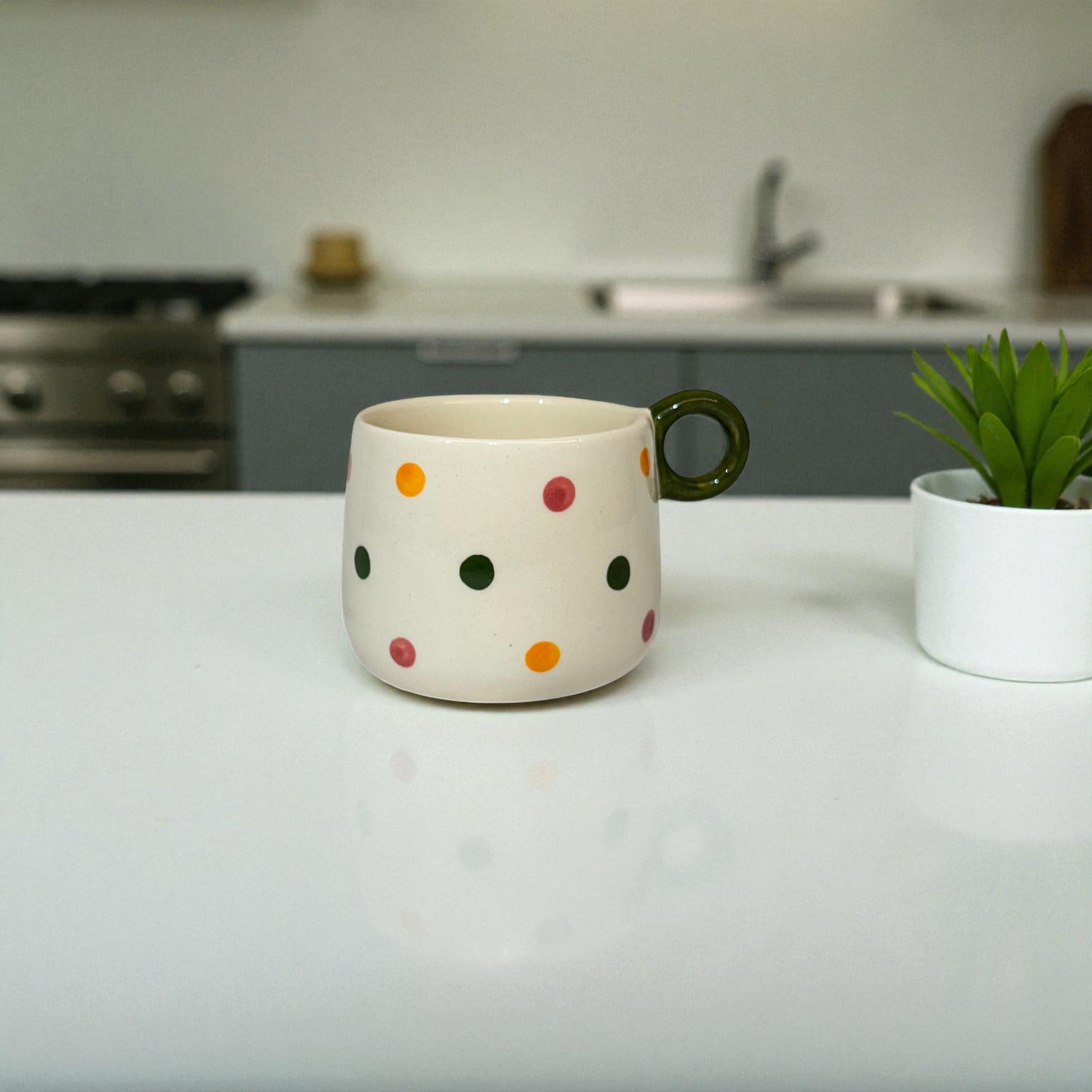 Polka dot mug on a kitchen counter with a plant in the background