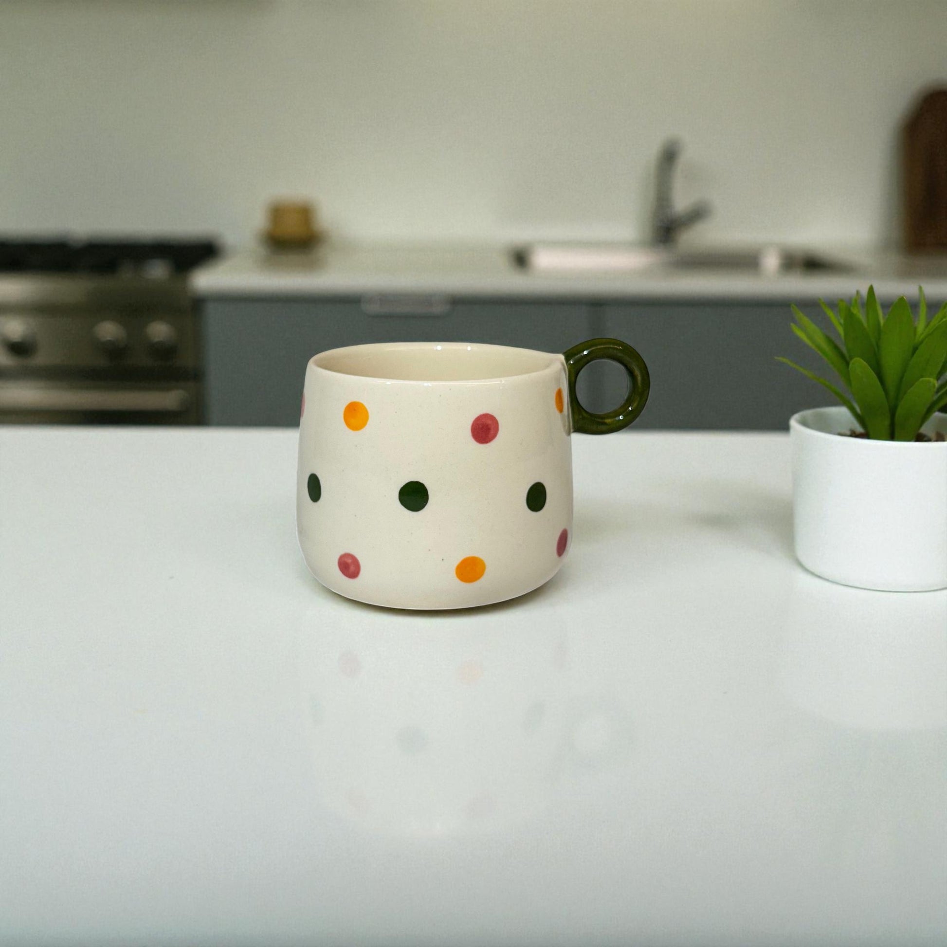 Polka dot mug on a kitchen counter with a plant in the background