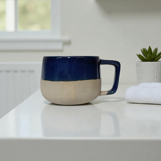 Two-tone ceramic mug with blue top and beige bottom on a white surface.