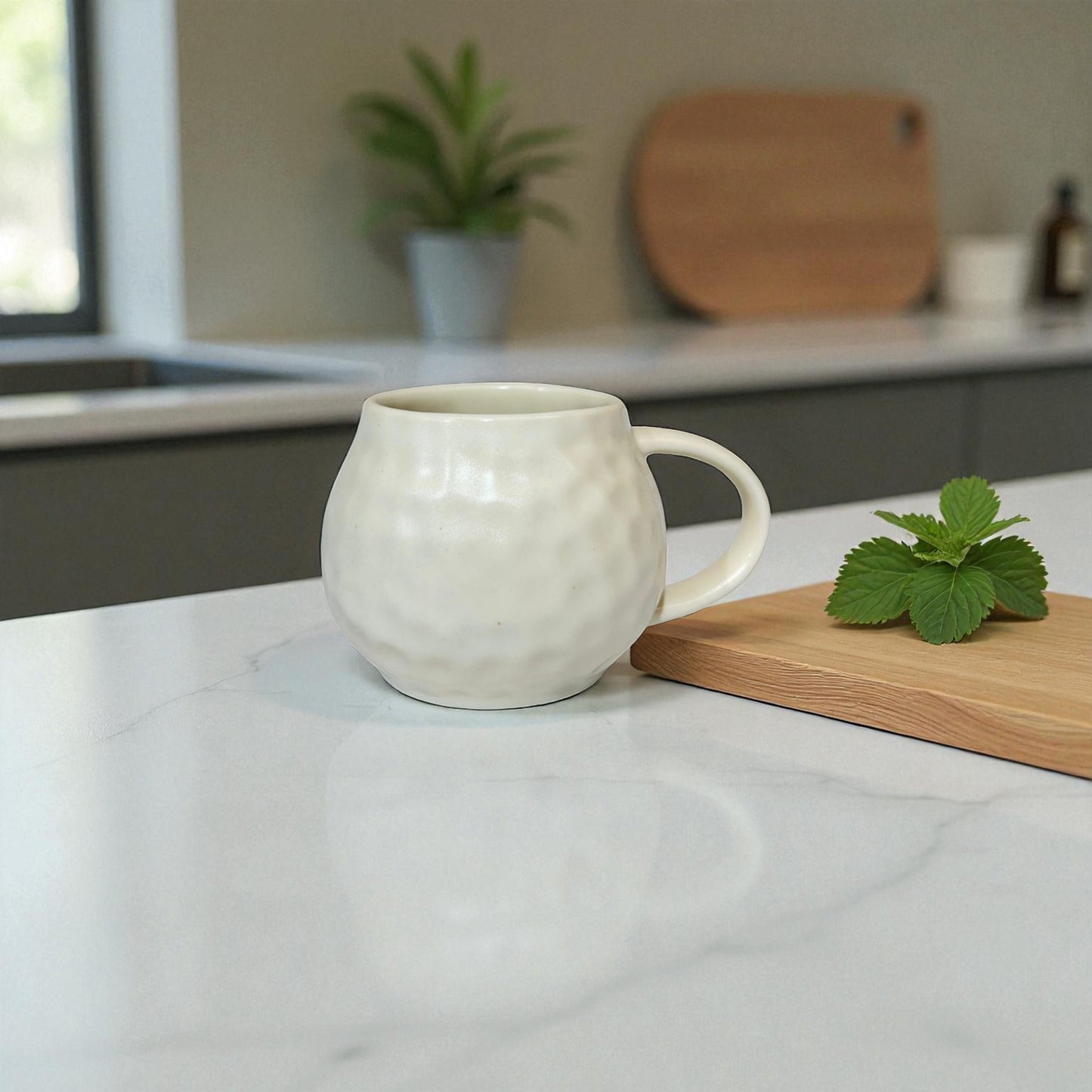 White ceramic mug on a marble countertop with a wooden cutting board and plant in the background.