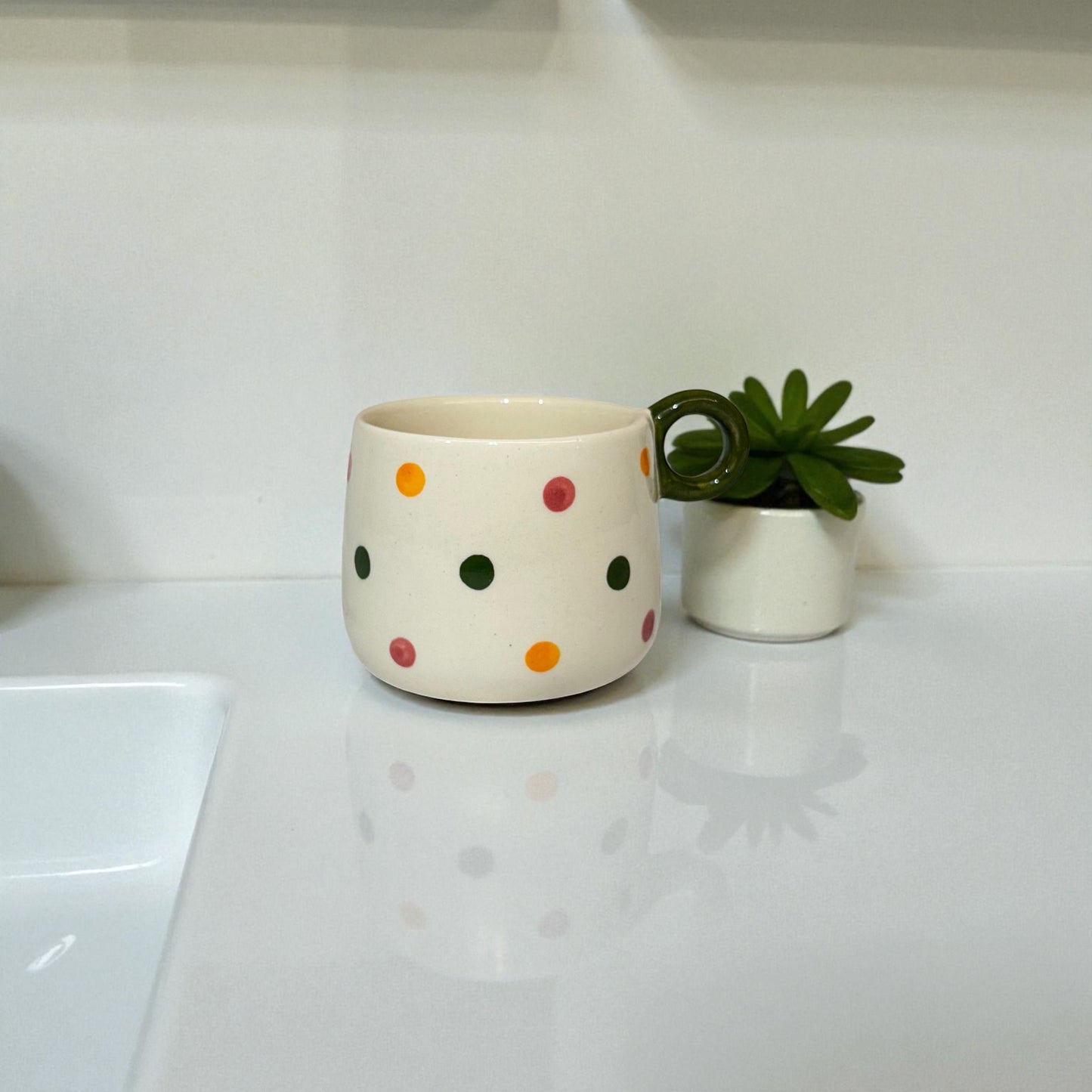 White ceramic mug with colorful polka dots on a white surface