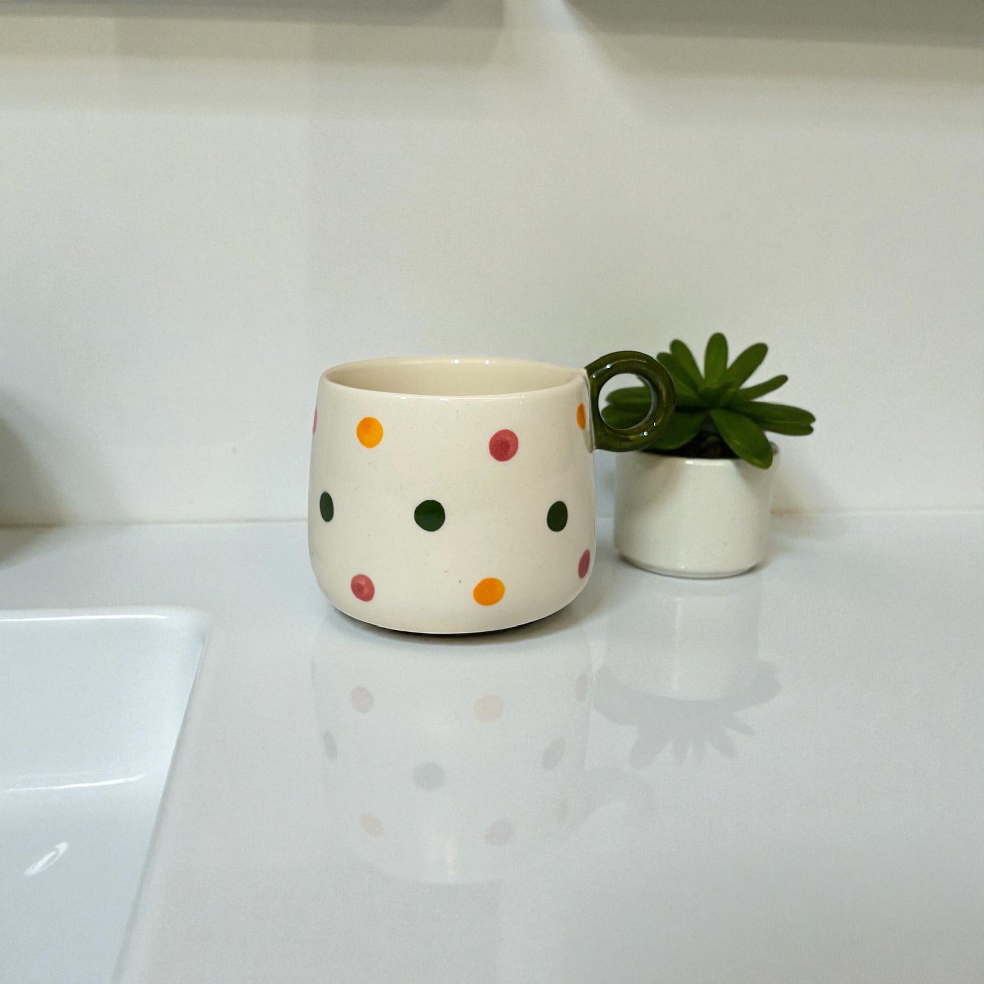 White ceramic mug with colorful polka dots on a white surface